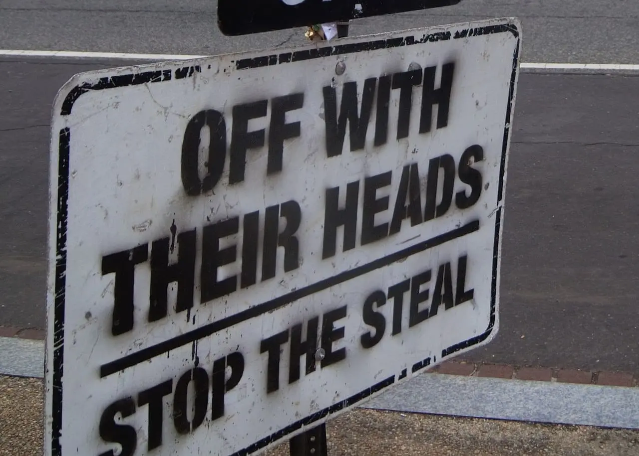 A sign that says, “OFF WITH THEIR HEADS, STOP THE STEAL”