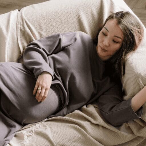 Good news pregnant woman lying on couch with her hand on her belly.