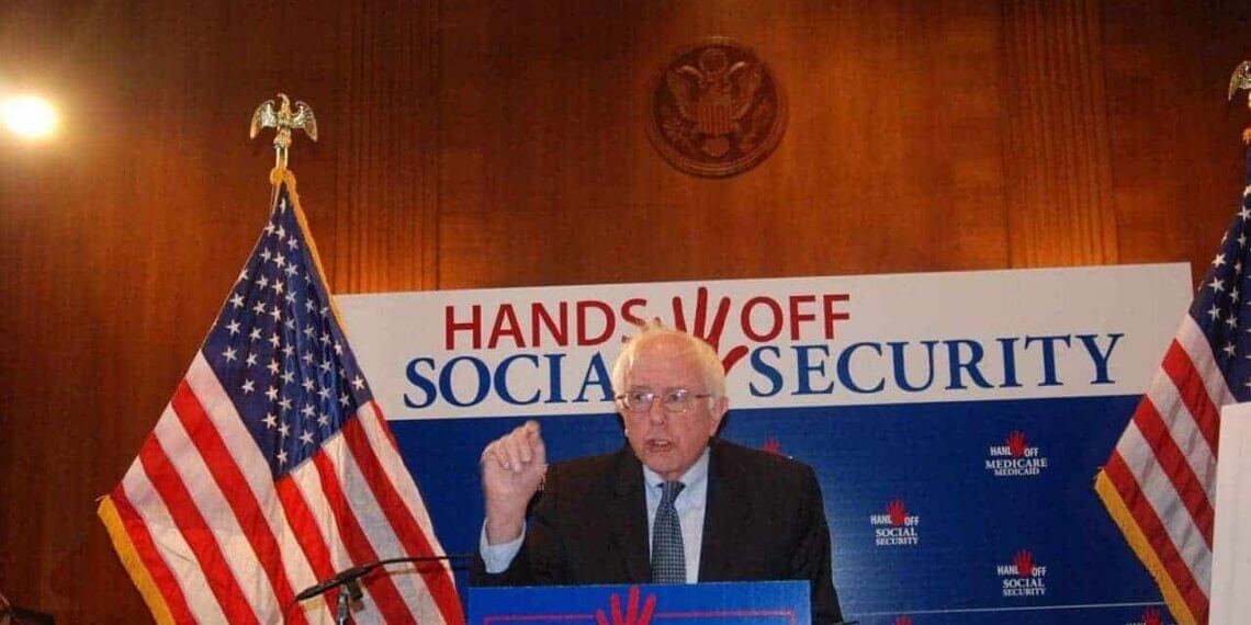 Progressive senator bernie sanders in front of a hands off social security banners