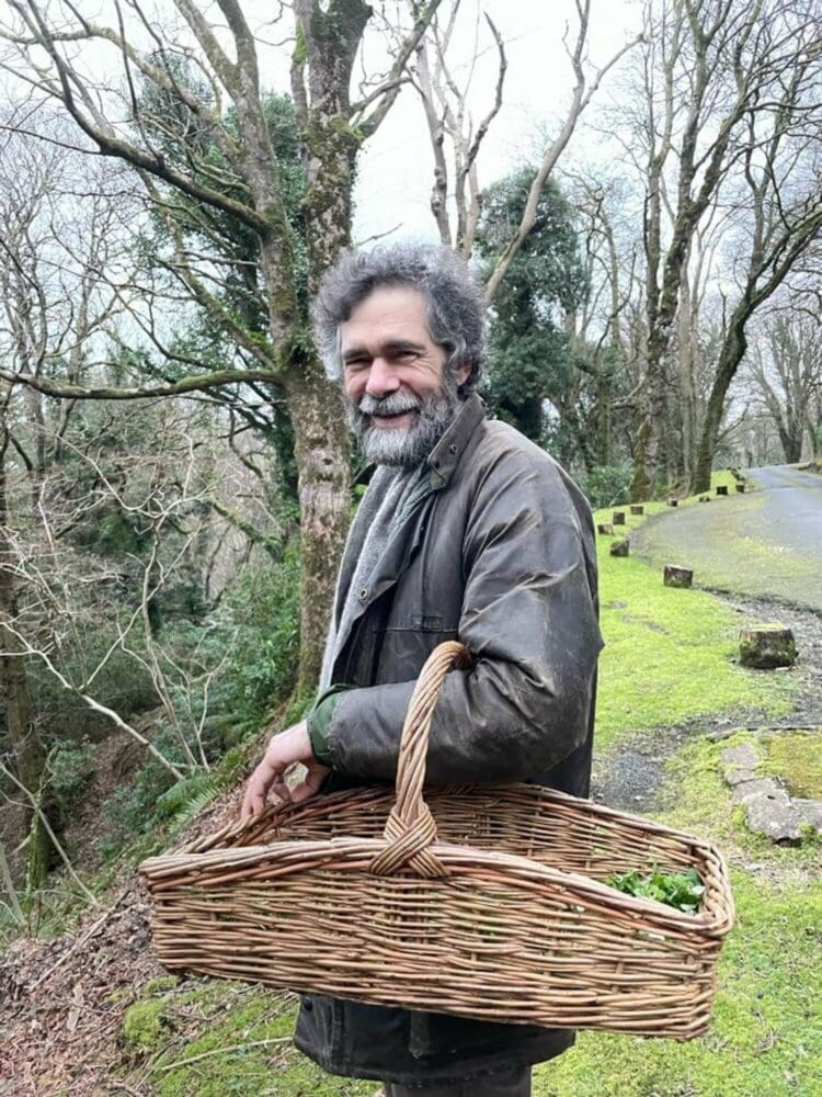 Richard Mawby in the woods with a wicker basket on his arm