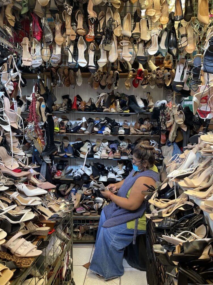 Chile shoe vendor sits among piles of shoes