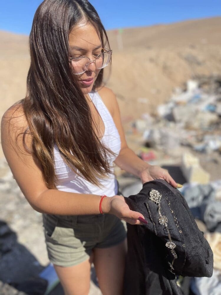 Chile desert clothing dump a woman holds a piece of clothing