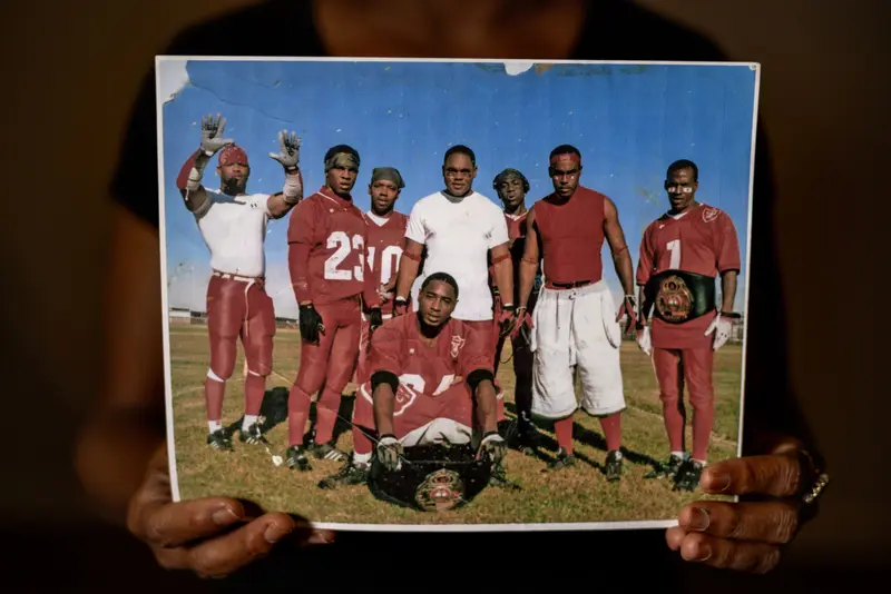 Someone holding a photo of Kentrell on the prison football team.