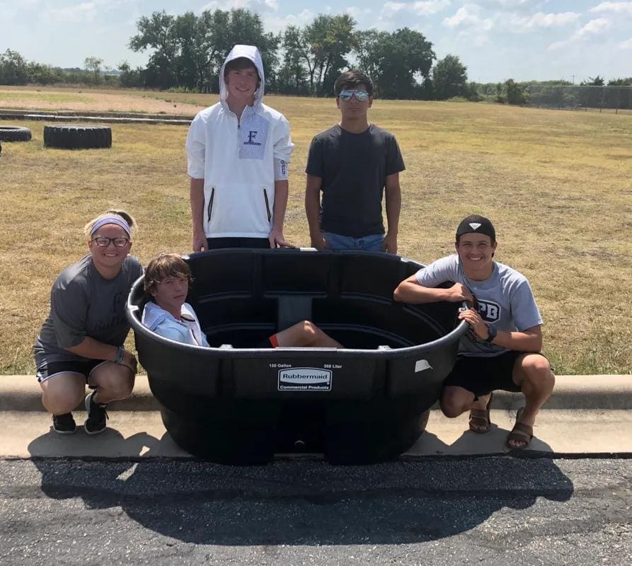 Teen boys stand around a cold tub used by football players to treat sore muscles.