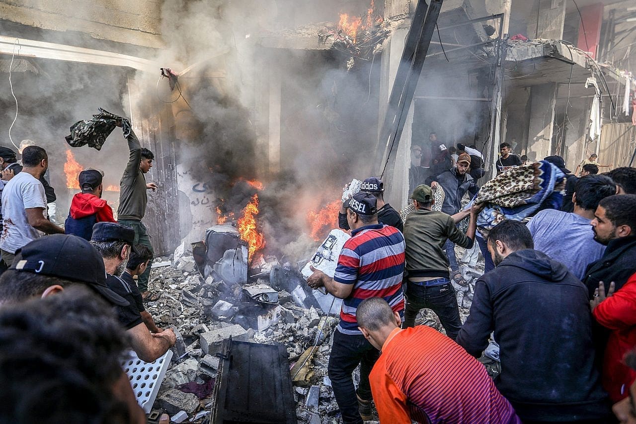 Palestinians survey the damage of an Israeli airstrike on a refugee camp