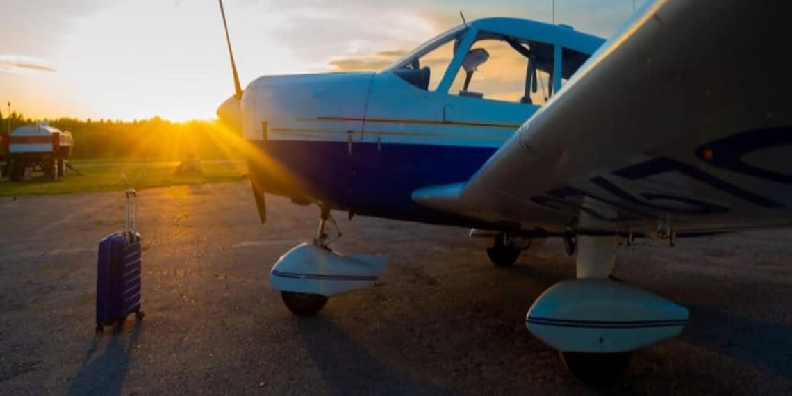 A small airplane on a runway with the sunset behind it.