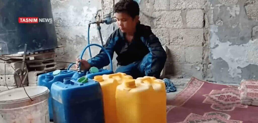 A palestinian chilld fills containers with water from a hose early in the war.