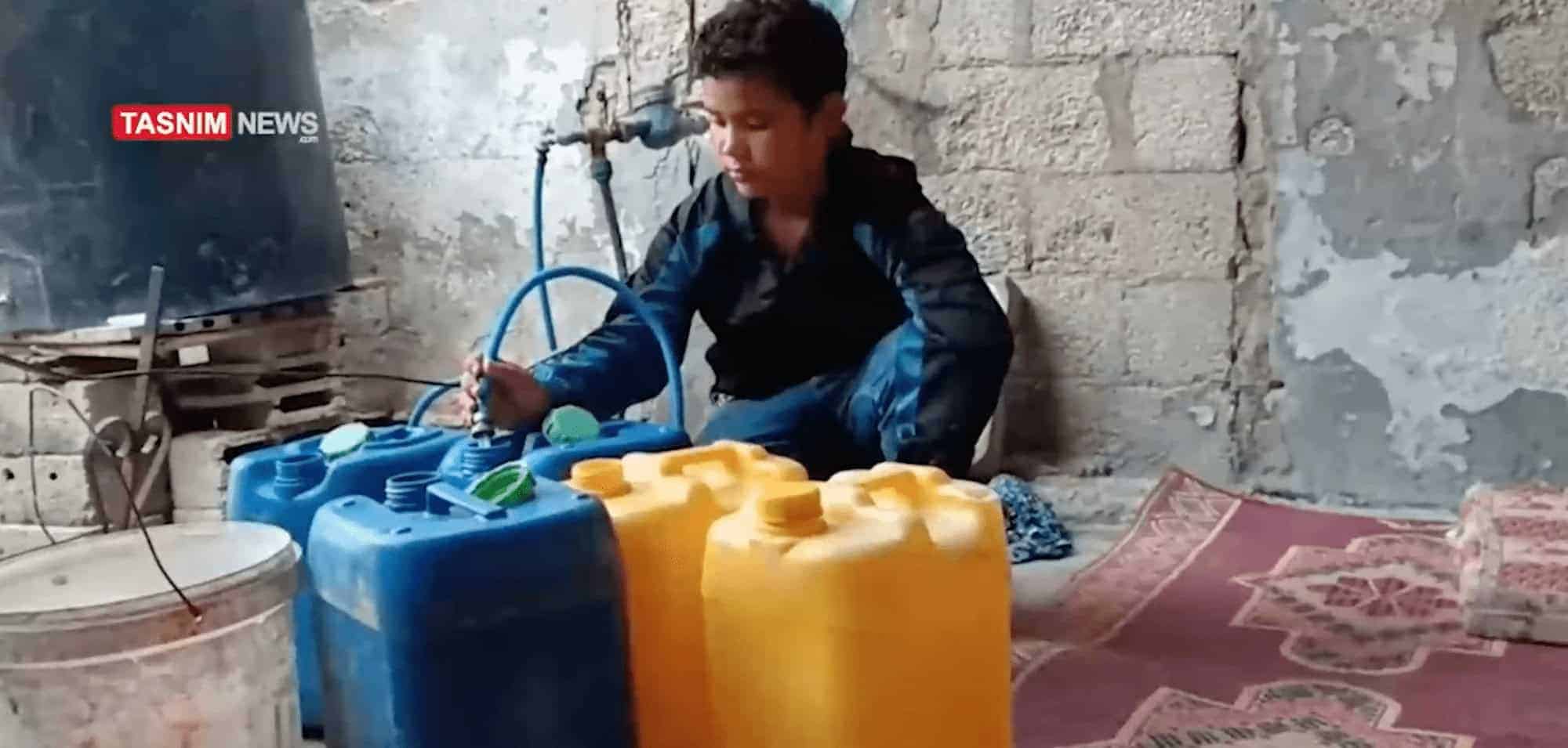 A palestinian chilld fills containers with water from a hose early in the war.