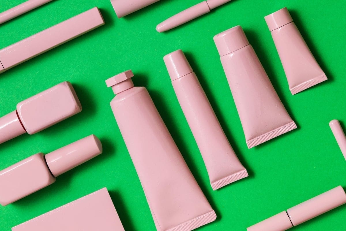 Generic pink beauty products on a green background.