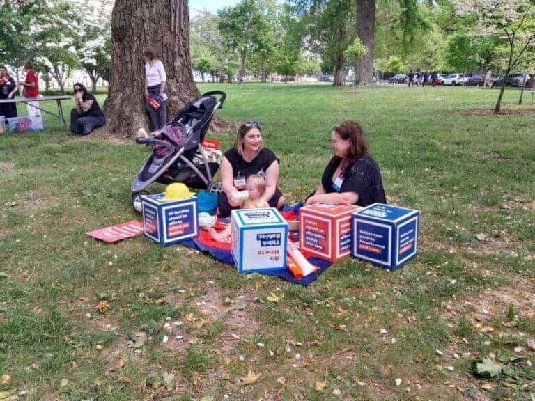 Mothers sit on the lawn while their kids are playing around them