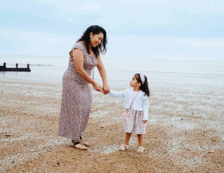 Mother and young daughter walking on the sand at the beach