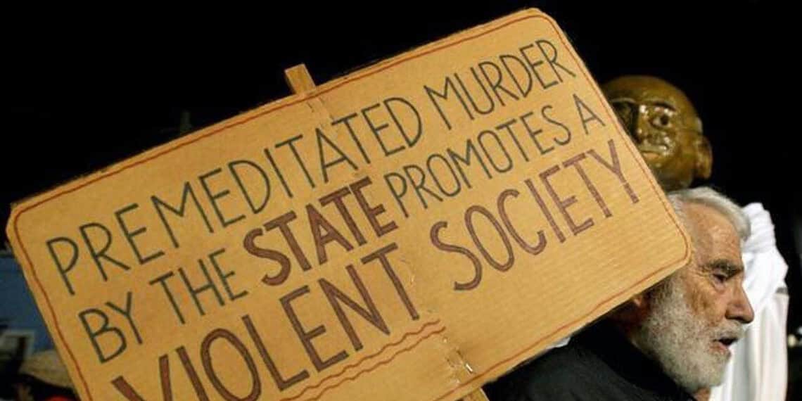 A pro-life protestor with a sign that says “premeditated murder by the state promotes a violent society”