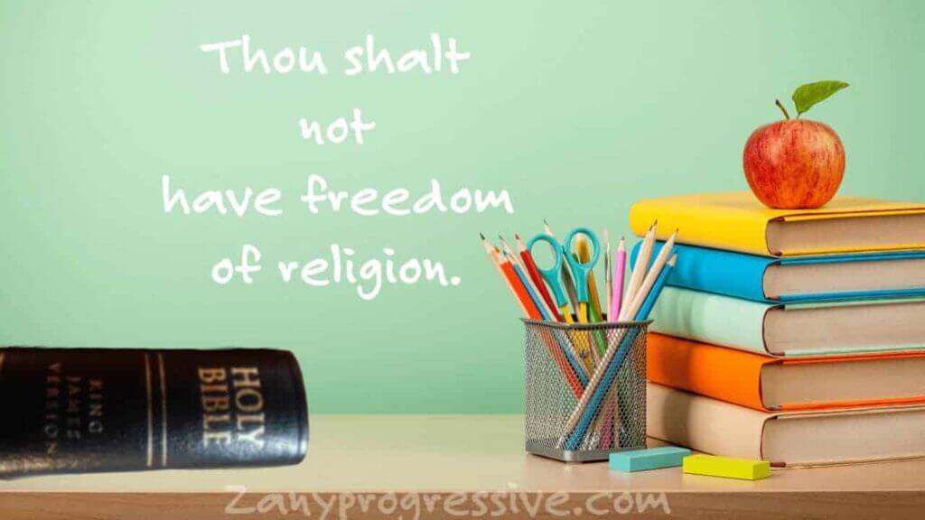Teachers desk at school with a bible on it and on the chalkboard behind it i