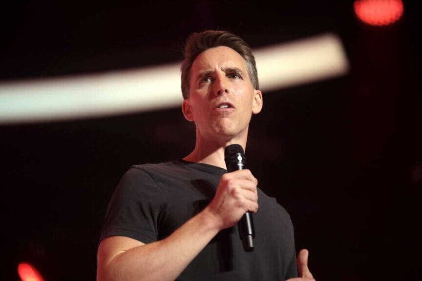 Josh hawley speaking on stage wearing a black t-shirt