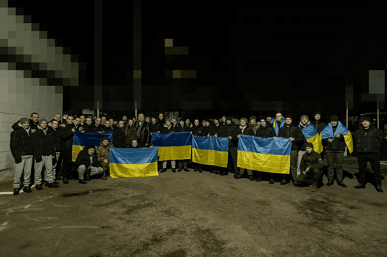 Soldiers in Ukraine war following a prisoner swap holding Ukrainian flags across the front row