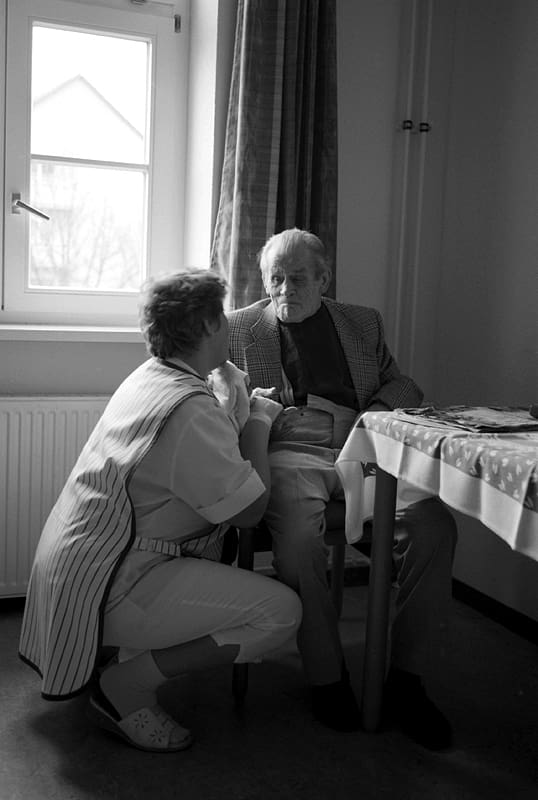 A nurse speaks to a patient in a nursing home