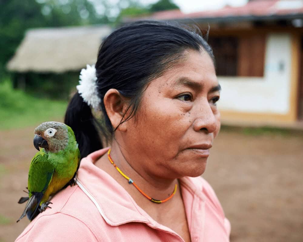 Planting trees to save the peruvian rainforest. A woman with a parrot on her shoulder