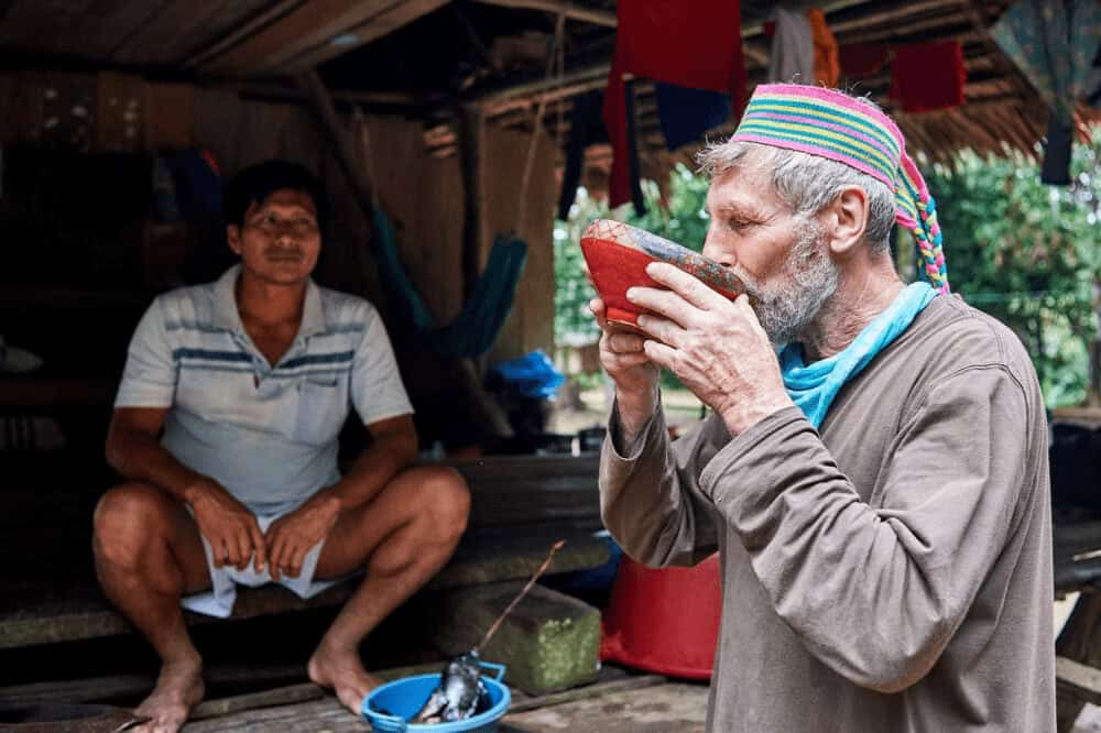 Planting trees rainforest. In peru a tourist drinks something from a red bowl.