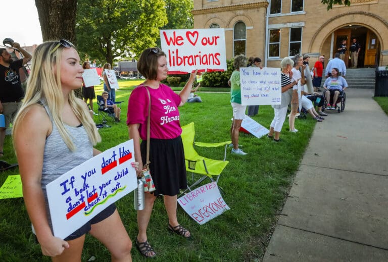 Kennedy Kasten, left, and Mollie Palmer, hold signs while protesting an ordinance that increases the Saline County Quorum Court’s control over the county’s library system. The quorum court voted for the measure during its monthly meeting at the Saline County Courthouse in Benton on Aug. 21, 2023.