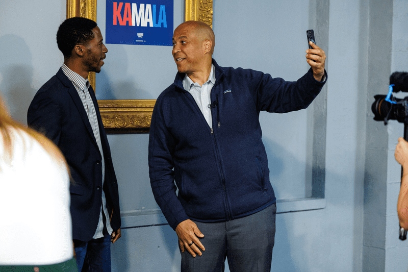 U.S. Sen. Cory Booker (D-N.J.), right, films social media content with Poke Bowl co-owner Jeron Dotson, left, after a roundtable with small business owners in Flint, Mich., on Sept. 20, 2024.