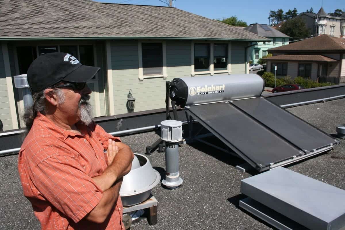 Hot water solar systems. A man on a roof next to his system