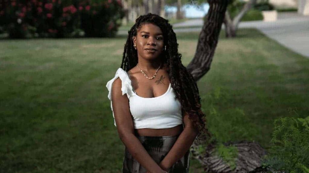 Black female college student posing in front of a tree