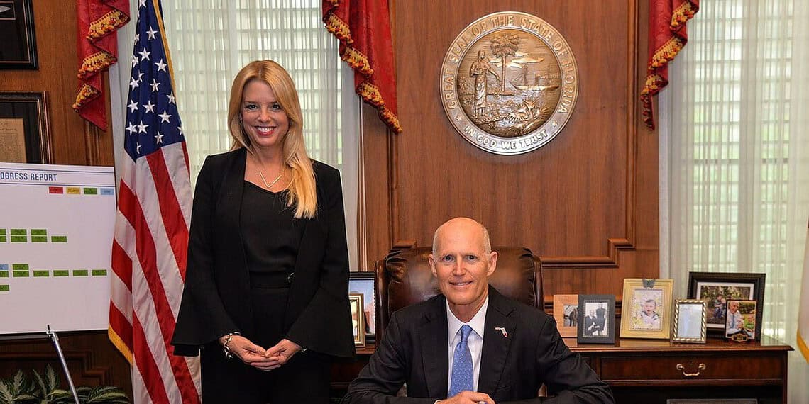 Pam bondi stands beside governor rick scott during a bill signing.