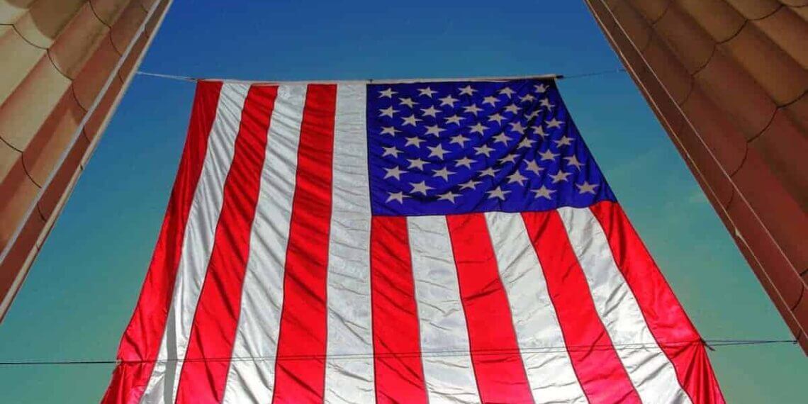 Underneath view of an american flag hanging with a blue sky in the background