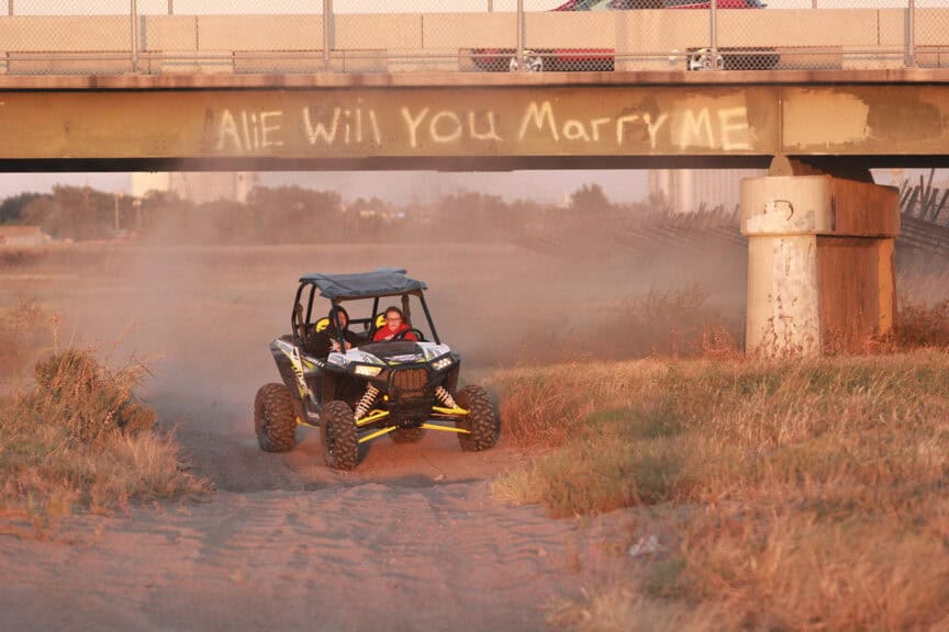 Kansas reflector opinion an atv driving through the dirt by the arkansas river under a bridge with “will you marry me” scrawled in the dirt