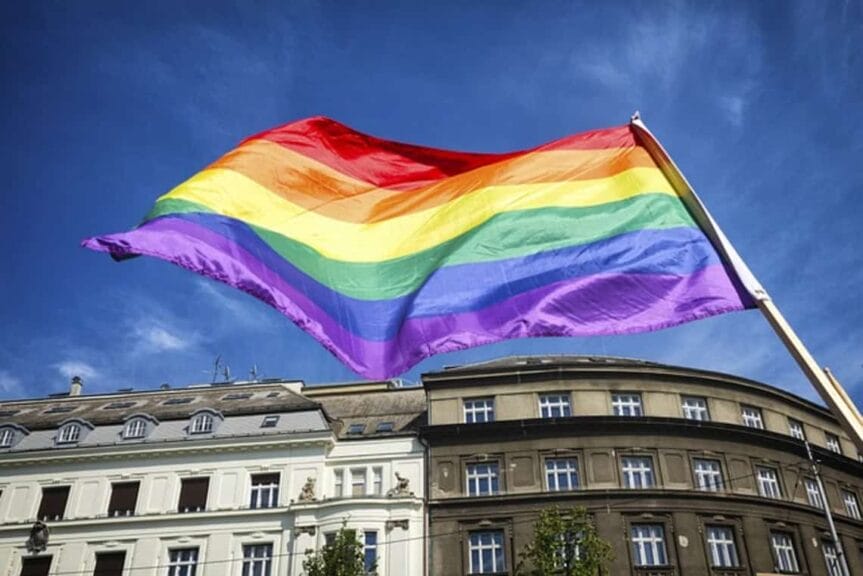 Trans rights are under attack. A rainbow flag in a city blows in the wind