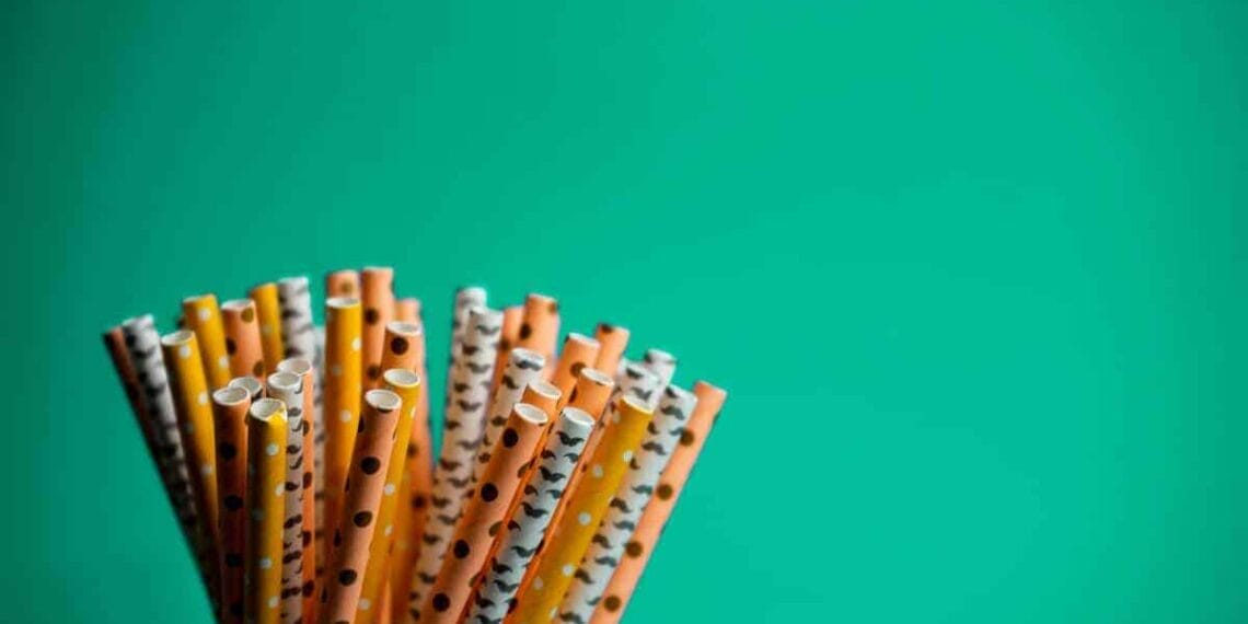 Colorful plastic straws on a green background