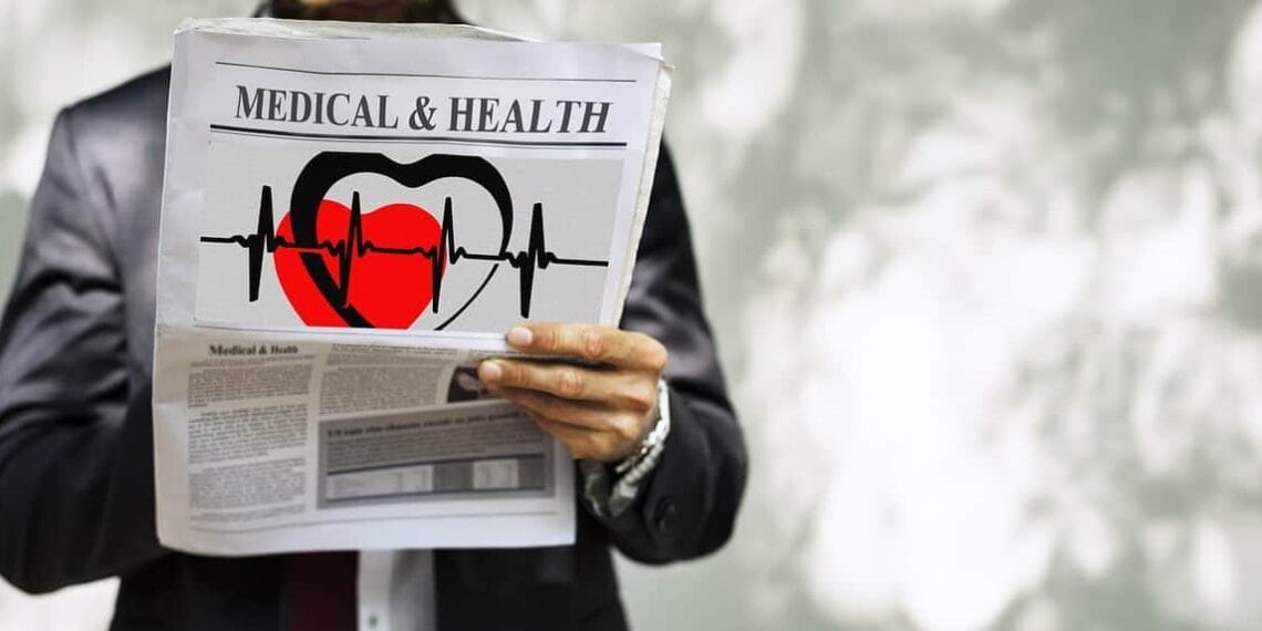 Man in suit holding a newspaper with medical & health headline