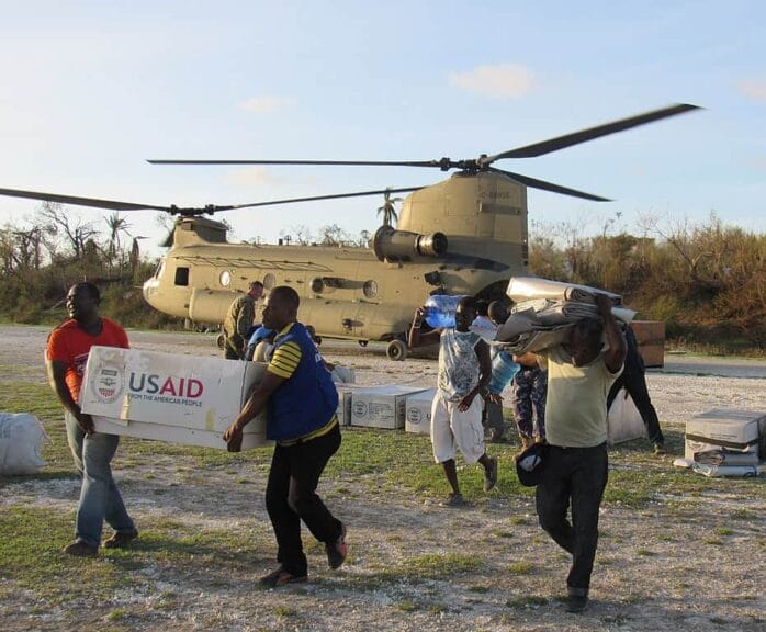 Foreign aid workers carry boxes marked with usaud from a helicopter in haiti