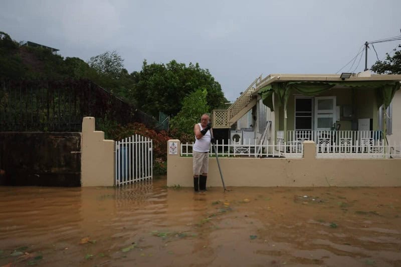 Man standing in flood waters in front of his home