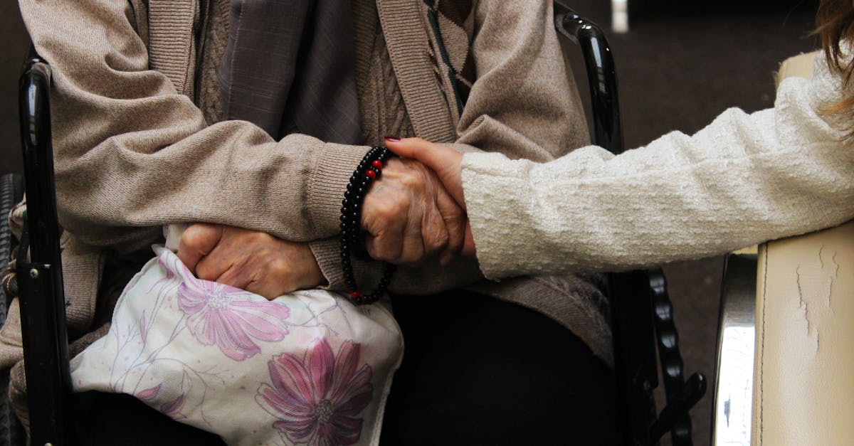 00 taken out of his bank account. Elderly woman in wheelchair warmly holding another's hand, symbolizing care and support.