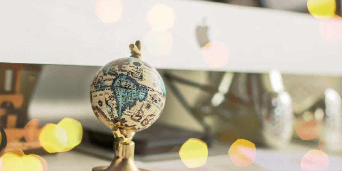 Close-up of a miniature globe on an office desk with a bokeh light effect, creating a dreamy atmosphere.