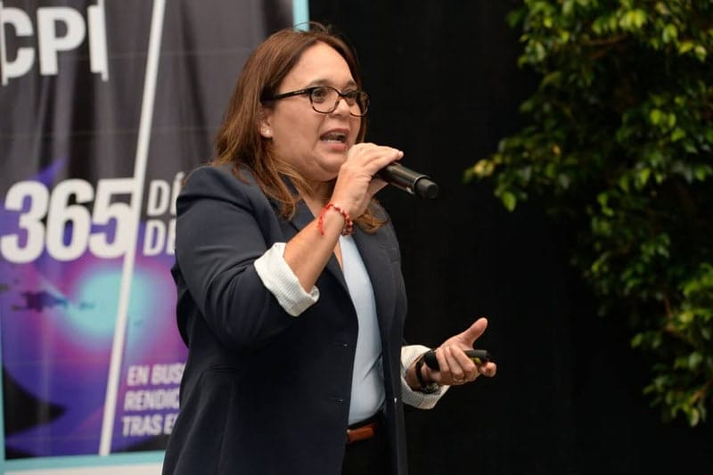 Research in puerto rico a woman speaks on stage holding a microphone.
