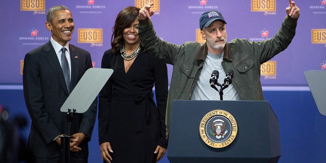 Jon stewart on stage with the obamas