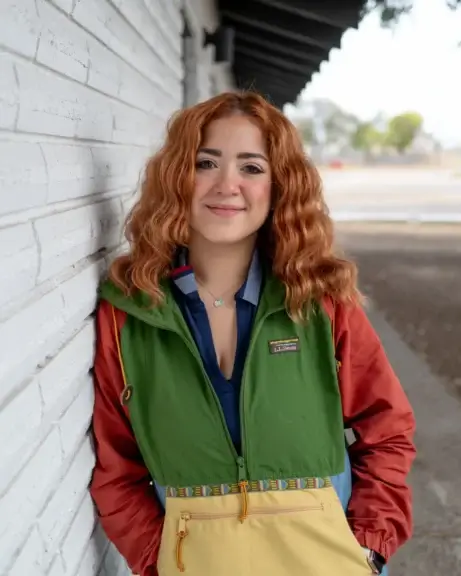 Community organizer with long red hair and colorful clothing says the community needs resources, not border security.