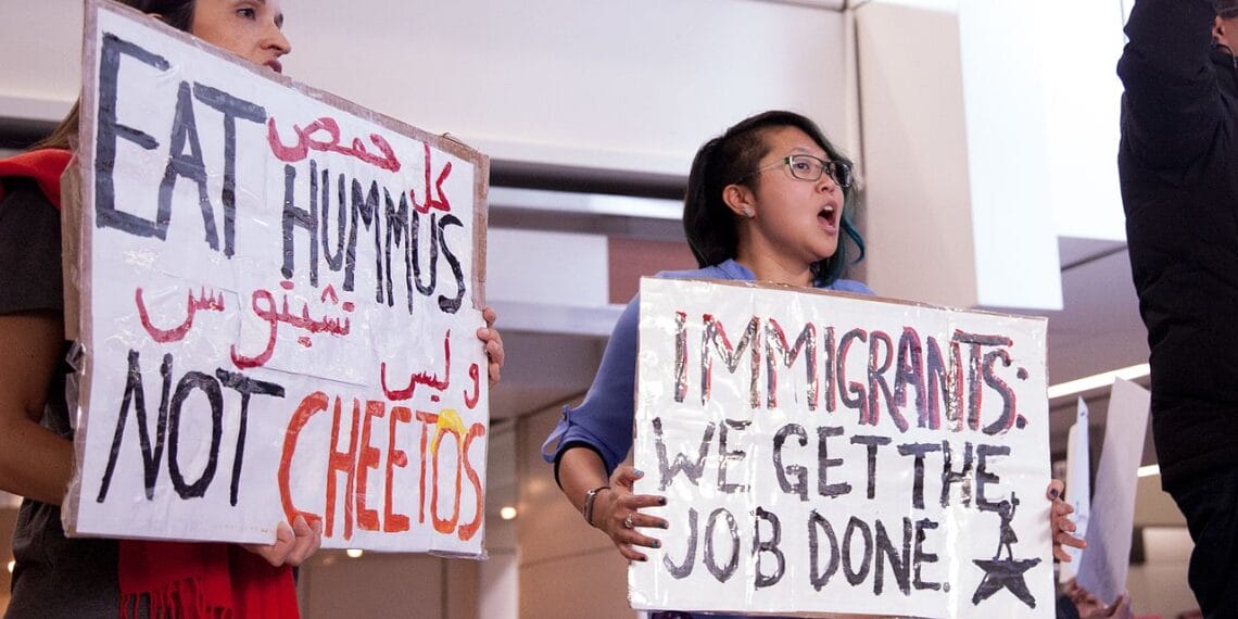 Immigrants protest with a sign that says immigrants get the job done