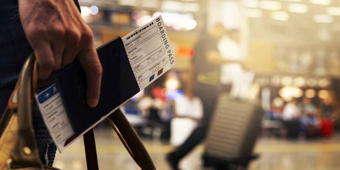 Man holding a passport and boarding pass in an airport
