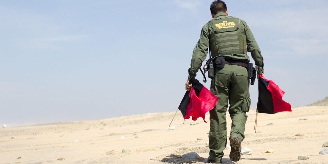Border patrol agent picking up flags