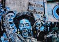 Social media vetting of student visa applicants began after student arrests for protesting. Urban art on a building of protesters.