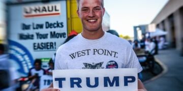 Donald trump at west point. A west point graduate holds a trump sign.