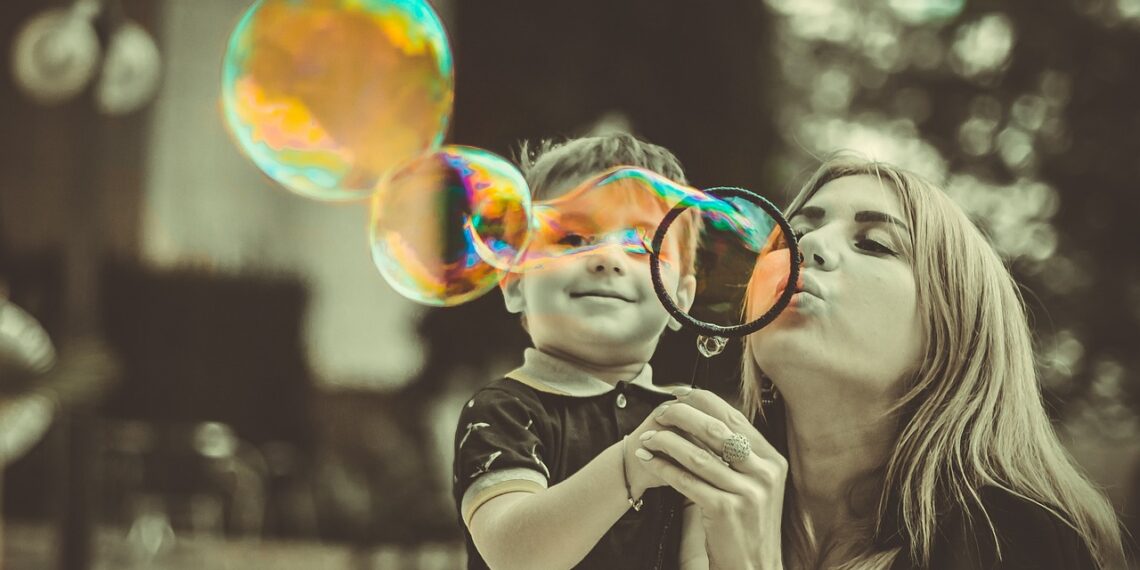 Mom holding a toddler, blows bubbles. Trump attacks college students who are parents.