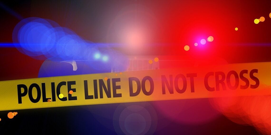 Violent crime. Blurry police car lights in the background behind yellow crime tape