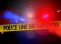 Violent crime. Blurry police car lights in the background behind yellow crime tape